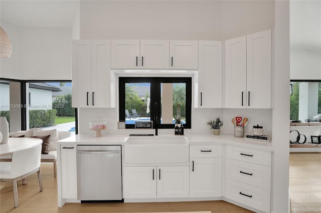 kitchen with white cabinetry, a wealth of natural light, stainless steel dishwasher, and light hardwood / wood-style floors