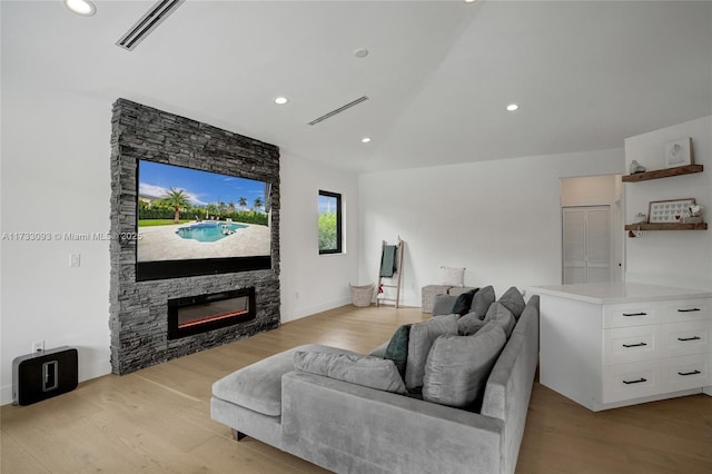 living room featuring lofted ceiling, a fireplace, and light wood-type flooring