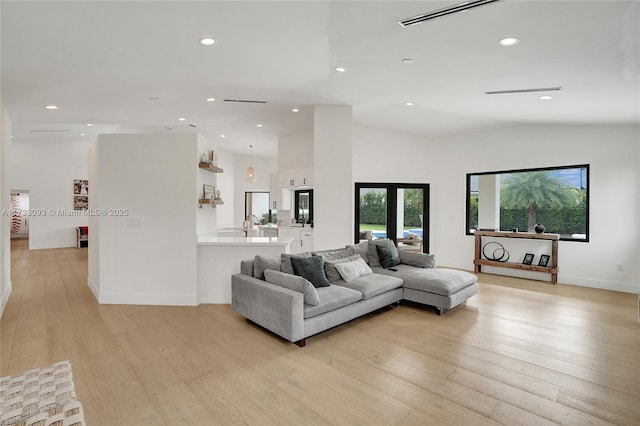 living room featuring lofted ceiling, french doors, and light wood-type flooring