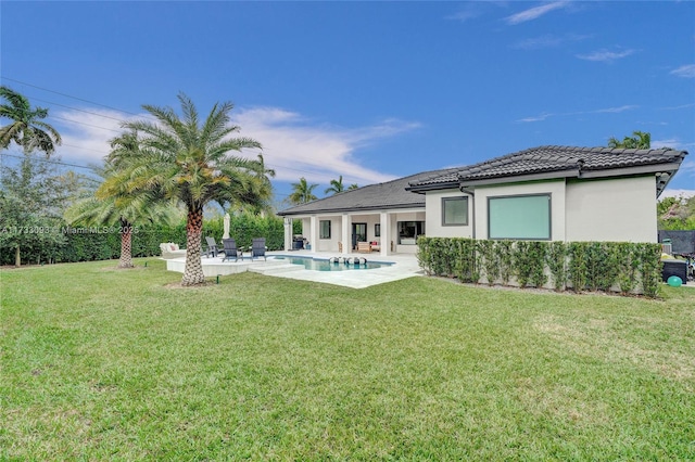 back of house with a fenced in pool, a patio, and a lawn