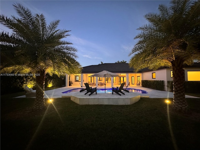 pool at dusk with a patio and an in ground hot tub