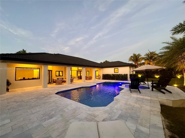 pool at dusk with a patio area