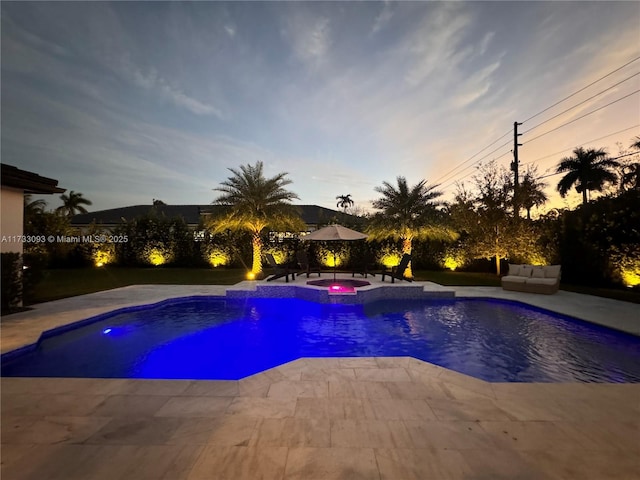 pool at dusk with an in ground hot tub and a patio area