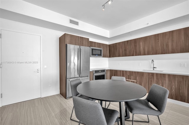 kitchen with appliances with stainless steel finishes, sink, track lighting, and kitchen peninsula