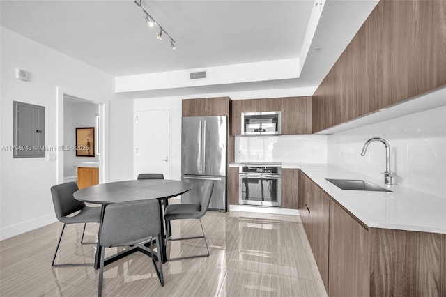 kitchen featuring appliances with stainless steel finishes, tasteful backsplash, sink, a breakfast bar area, and electric panel