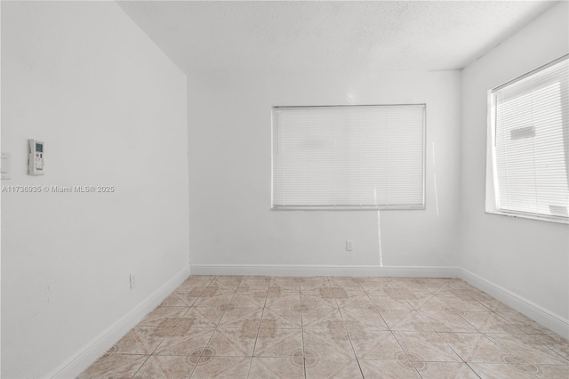 spare room featuring light tile patterned floors and a textured ceiling