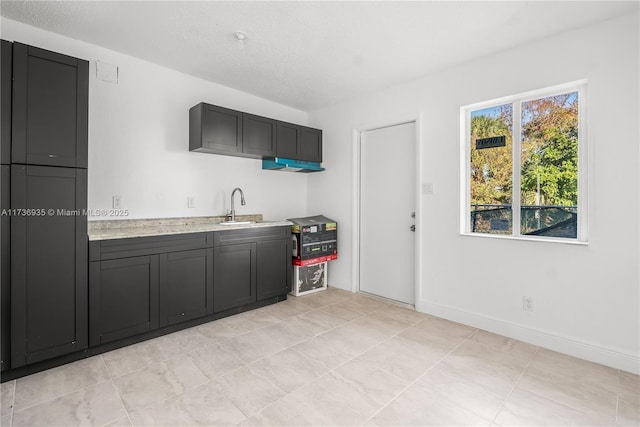 kitchen with sink, light stone countertops, and a textured ceiling