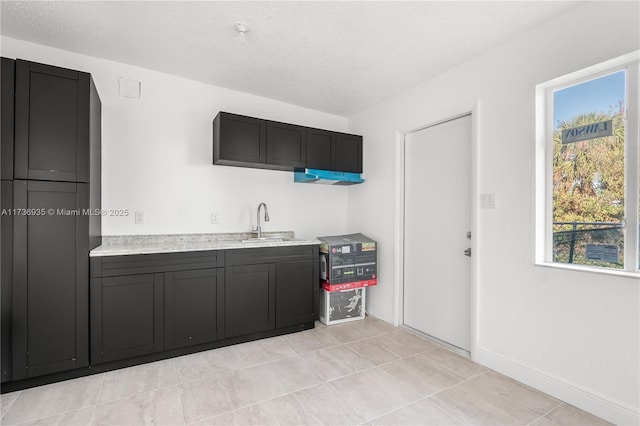 kitchen with sink, a textured ceiling, and light tile patterned floors