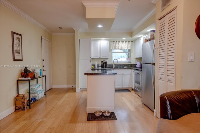 kitchen featuring appliances with stainless steel finishes, sink, white cabinets, ornamental molding, and light hardwood / wood-style flooring