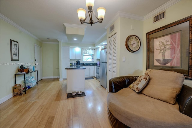 kitchen with white cabinetry, hanging light fixtures, stainless steel fridge, and ornamental molding