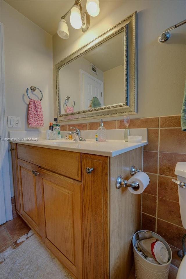 bathroom with tile patterned flooring, vanity, tile walls, and toilet