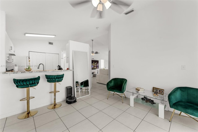 kitchen featuring vaulted ceiling, light tile patterned floors, white cabinets, and ceiling fan