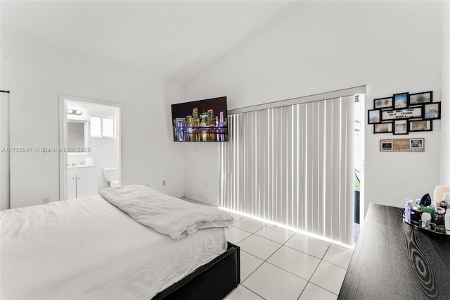 bedroom featuring ensuite bath, vaulted ceiling, and light tile patterned flooring