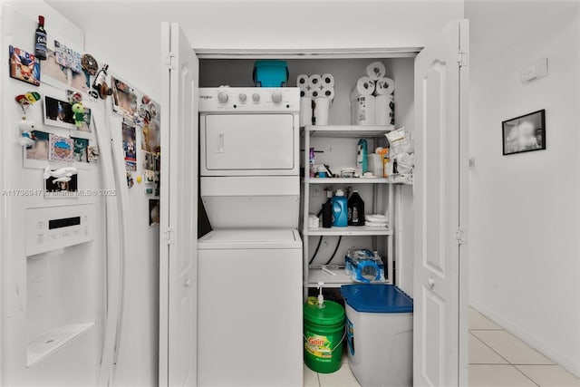 laundry room with light tile patterned floors and stacked washer / dryer