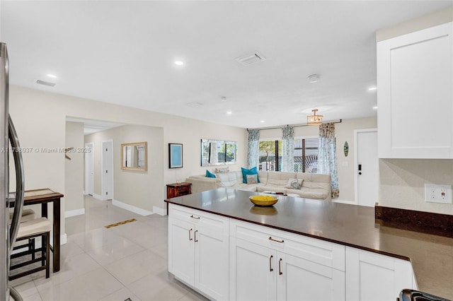 kitchen featuring light tile patterned floors, white cabinets, and stainless steel refrigerator