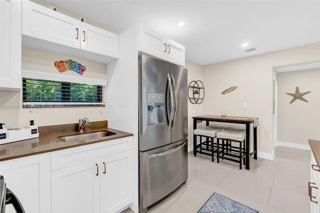 kitchen with white cabinetry, sink, stainless steel fridge, and light tile patterned flooring