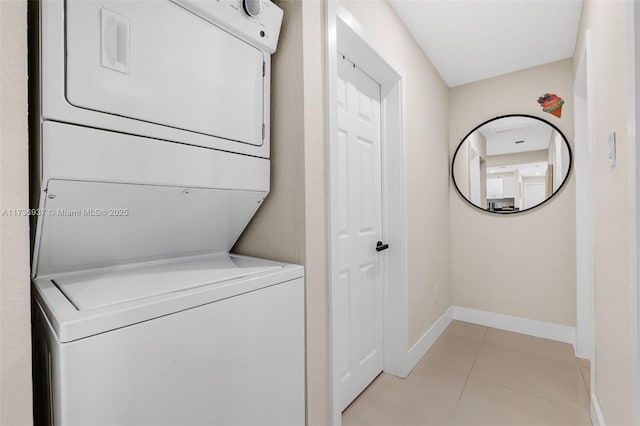 laundry area featuring stacked washer / drying machine and light tile patterned floors