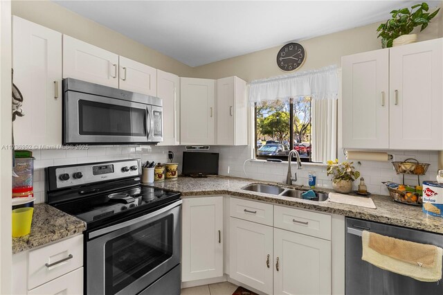 kitchen with white cabinetry, appliances with stainless steel finishes, sink, and light stone counters