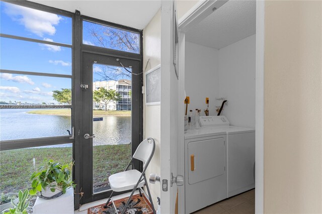 clothes washing area with tile patterned flooring, washer and dryer, and a water view