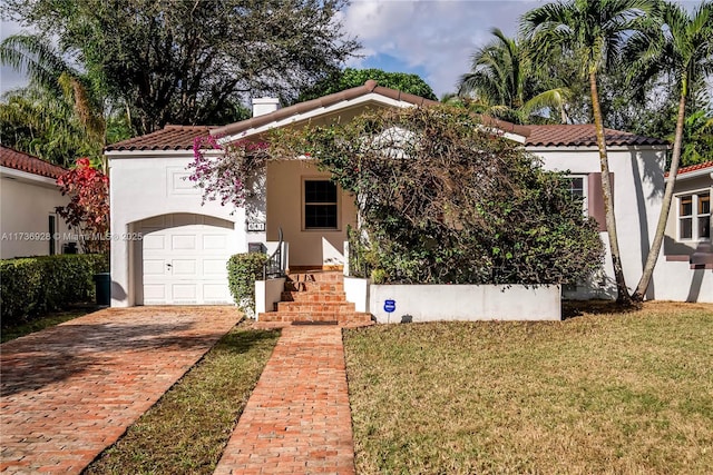 mediterranean / spanish home featuring a garage and a front lawn