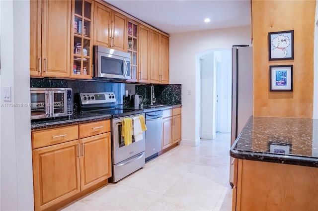 kitchen with stainless steel appliances, tasteful backsplash, sink, and dark stone countertops