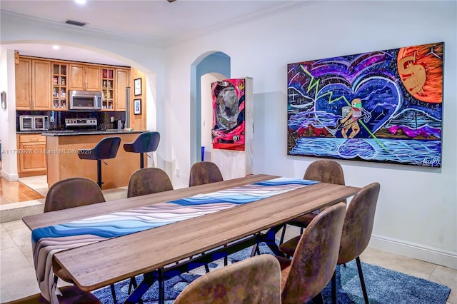 dining area with crown molding and light tile patterned floors