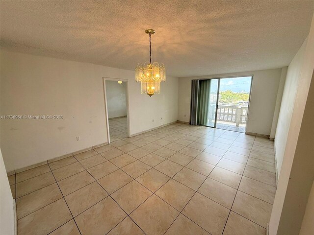 empty room with a notable chandelier, a textured ceiling, and light tile patterned floors