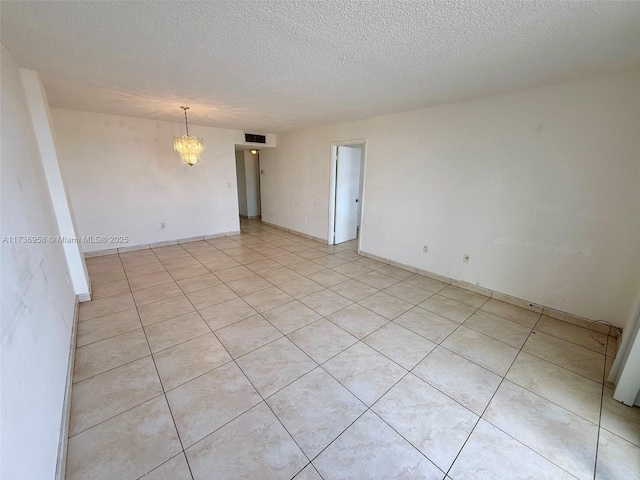 unfurnished room featuring a textured ceiling, visible vents, and a notable chandelier