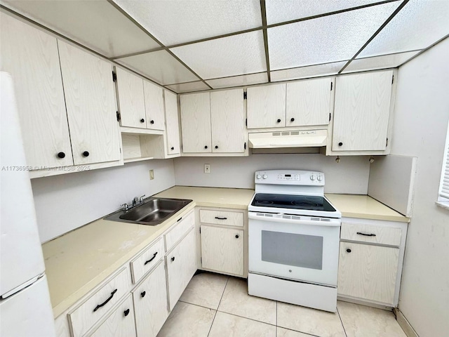 kitchen with a drop ceiling, under cabinet range hood, white appliances, a sink, and light countertops