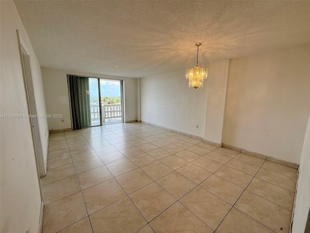 unfurnished room with light tile patterned floors, baseboards, a chandelier, and a textured ceiling