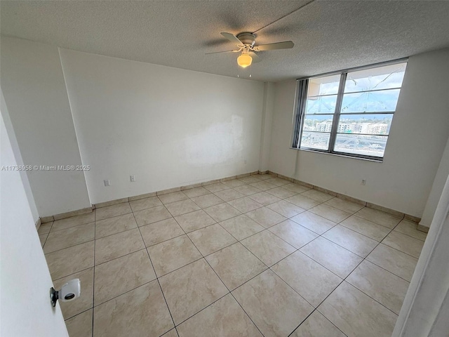 spare room with light tile patterned flooring, ceiling fan, and a textured ceiling