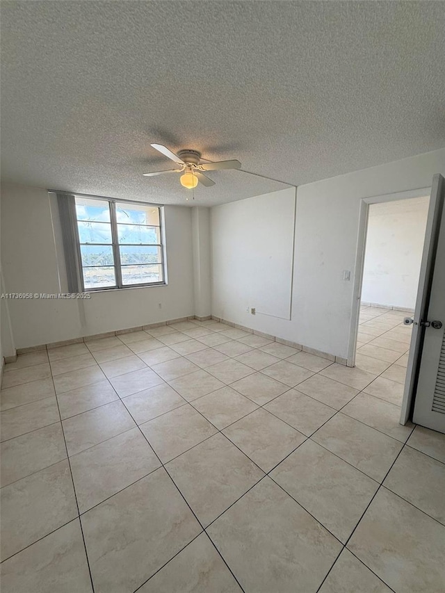 spare room featuring light tile patterned floors, ceiling fan, and a textured ceiling