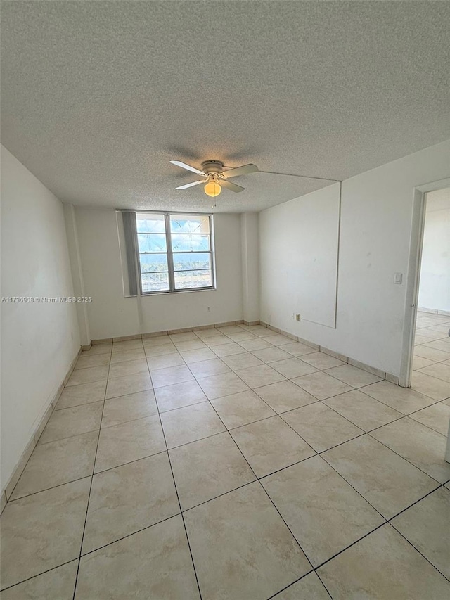 empty room with a textured ceiling, light tile patterned flooring, and a ceiling fan