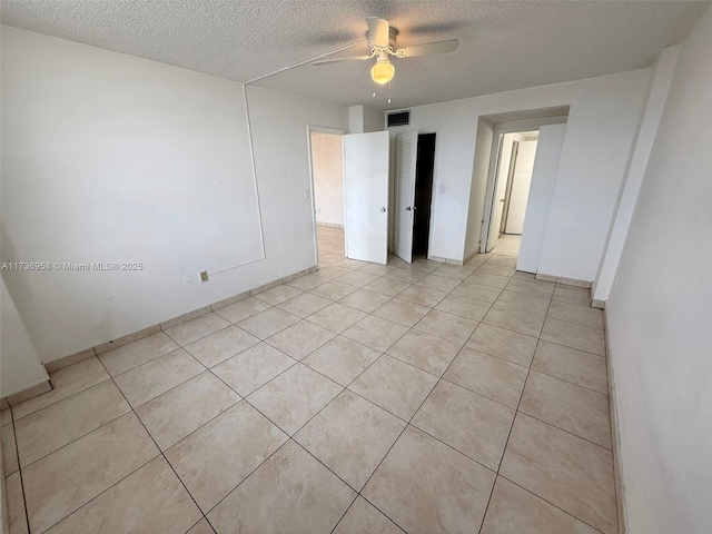 empty room with a ceiling fan, visible vents, a textured ceiling, and light tile patterned flooring