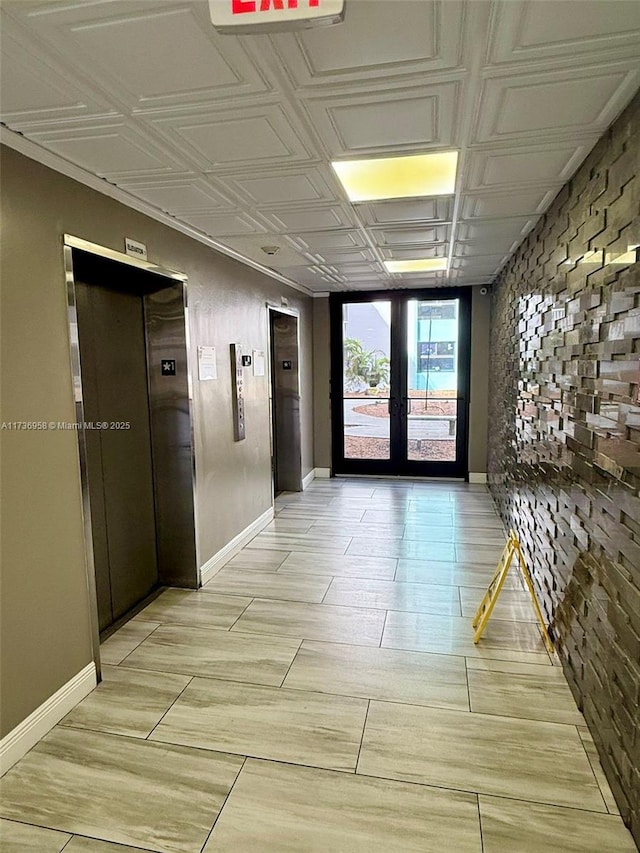 hallway featuring french doors, elevator, an ornate ceiling, and baseboards