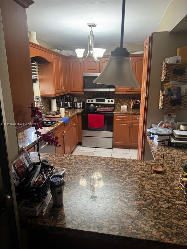 kitchen with light tile patterned flooring, appliances with stainless steel finishes, tasteful backsplash, dark stone counters, and hanging light fixtures