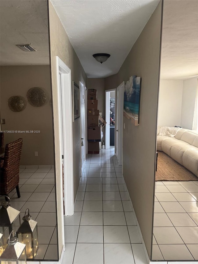 hallway featuring light tile patterned floors and a textured ceiling