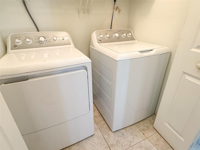 laundry area with washing machine and clothes dryer and light tile patterned floors