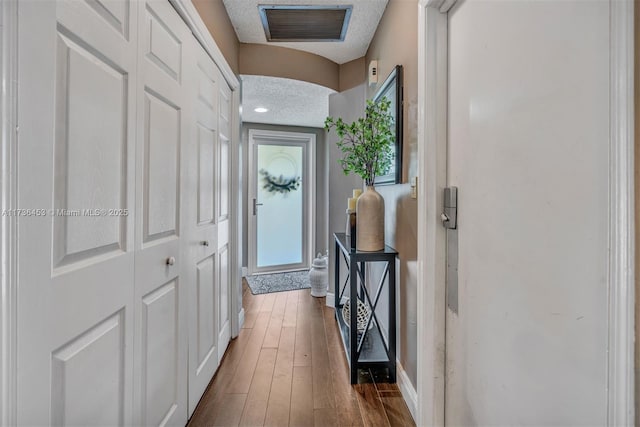 doorway with dark hardwood / wood-style floors and a textured ceiling