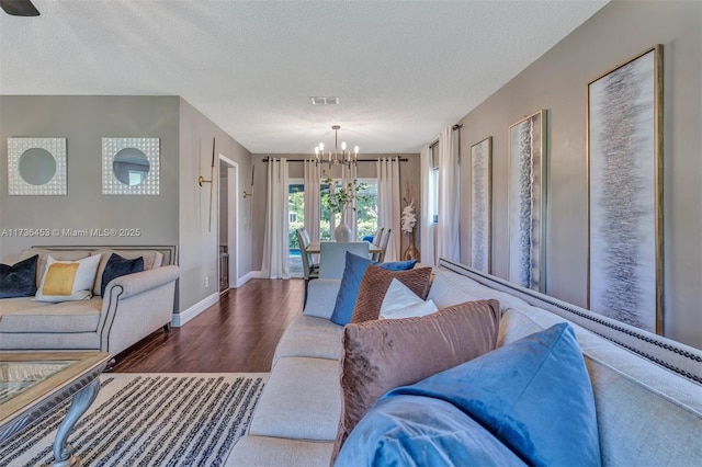 living room featuring an inviting chandelier, dark hardwood / wood-style flooring, and a textured ceiling