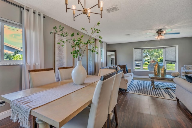 dining space with ceiling fan with notable chandelier, dark hardwood / wood-style floors, and a textured ceiling