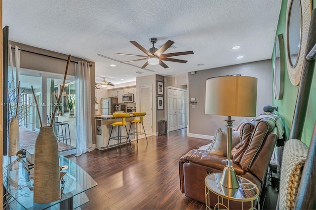 living room with dark hardwood / wood-style flooring, a textured ceiling, and ceiling fan