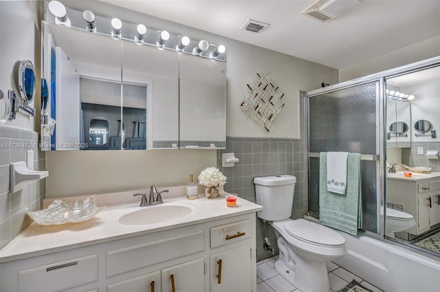 full bathroom with toilet, combined bath / shower with glass door, tile walls, vanity, and tile patterned flooring