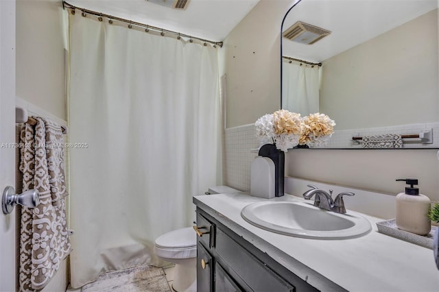 bathroom with vanity, toilet, and tile walls