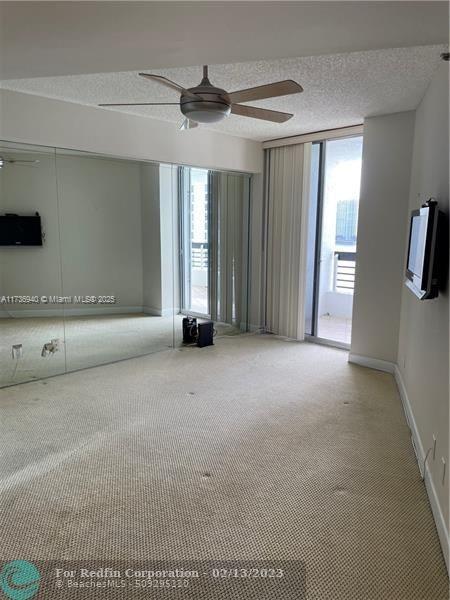 unfurnished room with ceiling fan, carpet floors, expansive windows, and a textured ceiling