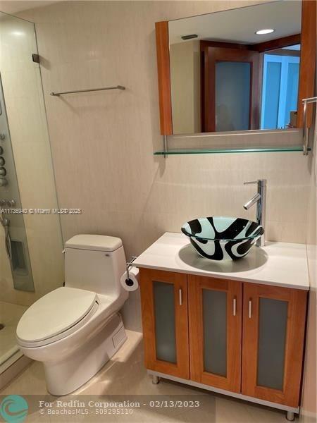 bathroom with vanity, decorative backsplash, a shower, and toilet