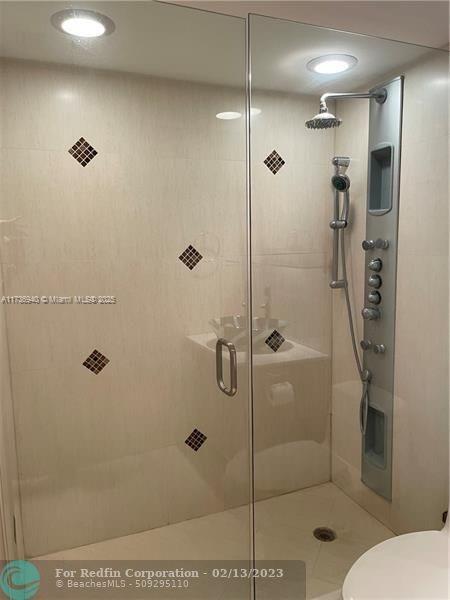 bathroom featuring toilet and a shower with shower door