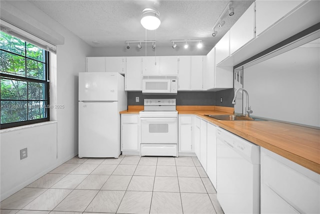 kitchen with light tile patterned flooring, sink, white cabinets, white appliances, and a textured ceiling