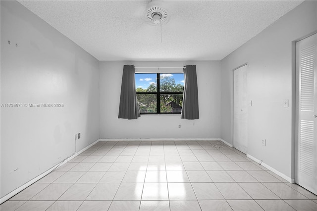 spare room featuring a textured ceiling and light tile patterned floors