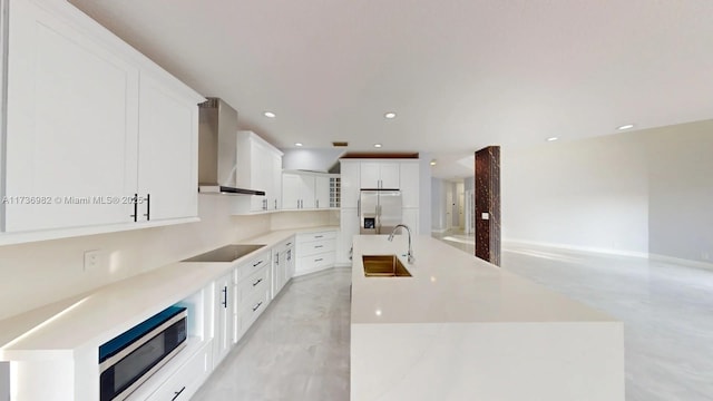 kitchen with wall chimney exhaust hood, sink, a center island, stainless steel appliances, and white cabinets